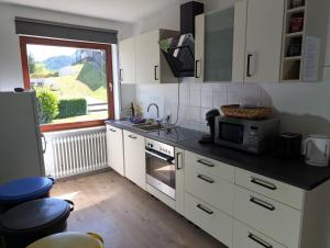 a kitchen with white cabinets and a microwave and a window at Das Spatzennest in Riol