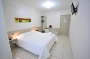 a bedroom with a white bed and a desk at Hotel FIT in Palmas