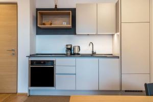 a kitchen with white cabinets and a black dishwasher at Ferienwohnungen Karin - Merlot in Termeno