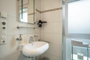 a bathroom with a white sink and a mirror at Familien-Apartment 2 in Meersburg +14 photos