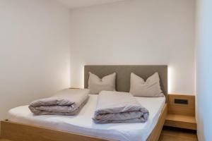 a bedroom with a bed with white sheets and pillows at Ferienwohnungen Karin - Merlot in Termeno