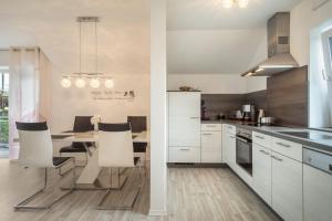 a kitchen with white cabinets and a table with chairs at Familien-Apartment 2 in Meersburg