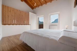 a white bedroom with a large bed and two windows at Family House Il Butto in Erve