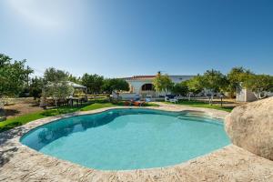 a swimming pool with a large rock next to a house at Villa Mavi in Quartucciu