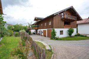 a large wooden house with a balcony and a driveway at Neubau - Ferienwohnung Waldblick in Höslwang