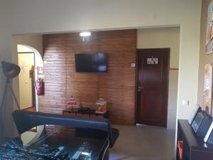 Habitación con pared de madera y TV. en Almancil Hostel, en Almancil