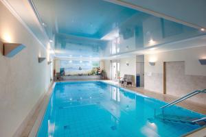 a large swimming pool with blue tiles in a building at Haus Schönblick - "Fewo Sarina 2" in Willingen