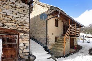 a stone building with snow on the side of it at Chalet Tomidicarta in Trasquera