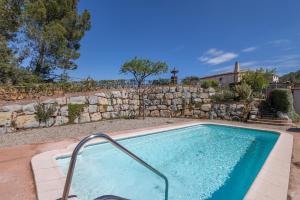 a swimming pool in a yard with a stone wall at Ca l'Emilli in Gélida