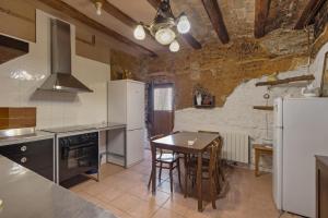 a kitchen with a table and a white refrigerator at Ca l'Emilli in Gélida