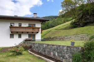 a white house with a stone wall next to a hill at Hienerhof in Moso