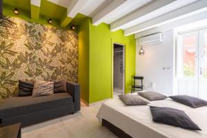 two beds in a room with green walls and a couch at Ortigiadreamrooms 12 in Syracuse