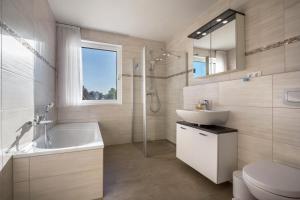 a bathroom with a sink and a tub and a toilet at Ferienhaus Lübeck Buntekuh in Lübeck +17 photos