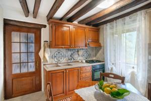 a kitchen with wooden cabinets and a table with a bowl of fruit at Agriturismo U' Spigu Nonna Annetta in Nasino