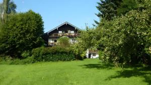 a house in the middle of a field with trees at Haus Elbrächter Ferienwohnung 2 in Gstadt am Chiemsee