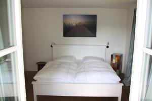 a bed with white sheets and pillows in a room at Haus Elbrächter - Erdgeschoss in Gstadt am Chiemsee