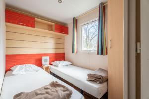 two beds in a small room with a window at Euro Mobil B16 in Boofzheim +80 photos