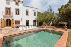 a swimming pool in front of a house at Masia Sant Miquel in Canet de Mar