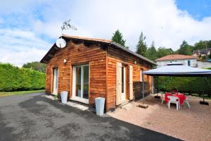 a small wooden cabin with a table and an umbrella at Chalet avec piscine privée in Savignac-les-Églises