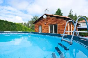 a swimming pool in front of a log house at Chalet avec piscine privée in Savignac-les-Églises