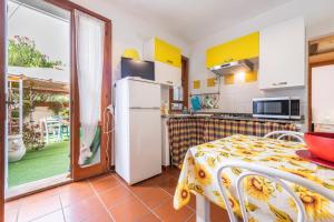 a kitchen with a table and a refrigerator and a door at Casa Leo in Calasetta