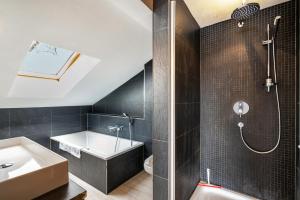 a bathroom with a tub and a sink and a shower at Wohnung am See in Gmund am Tegernsee +18 photos