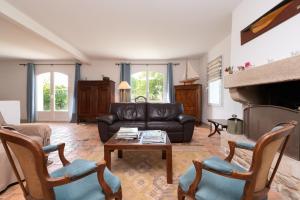 a living room with a black leather couch and a fireplace at Madig Azul Maison Piscine Chauffée in La Trinité-sur-Mer