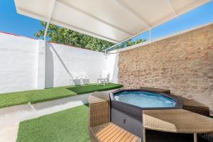 a hot tub in a patio with chairs and grass at La Bombonera 2 in Catadau