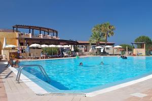 a swimming pool with people in the water at Le Gemelle al 212 in Villaputzu