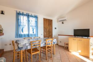 a dining room with a table and chairs and a television at Le Gemelle al 212 in Villaputzu
