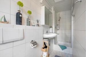a white bathroom with a sink and a shower at Ferienhaus Frieda in Röfingen +29 photos
