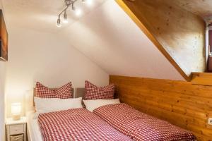 two beds with red and white checked pillows in a attic at Ferienwohnung Reschberg in Farchant