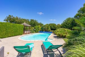 a swimming pool with two lawn chairs and a table at La Desirade in Saint-Agnant
