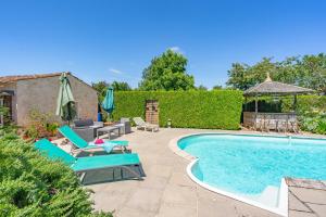 a swimming pool with chairs and a table and a umbrella at La Desirade in Saint-Agnant