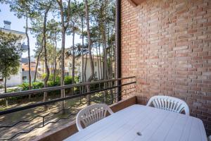 a white table and chairs on a balcony with a brick wall at Appartamento Andromeda B4 in Bibione