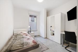 a white bedroom with a bed and a desk at Haus Rosa in Albstadt