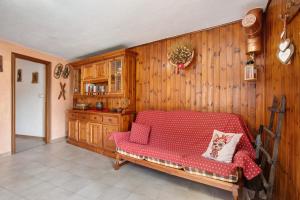 a living room with a red couch and wooden walls at Petite Maison Tillier in Fenis