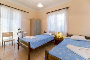 a bedroom with two beds and a table and a chair at Villa Captain Fotis 3 in Póndi