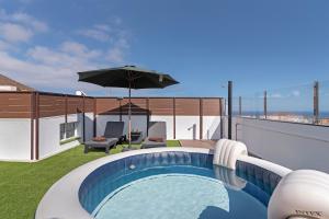 a swimming pool with an umbrella on a roof at One life one dream Gran Canaria in Carrizal