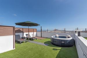 a backyard with a hot tub and an umbrella on a roof at One life one dream Gran Canaria in Carrizal