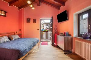 a bedroom with orange walls and a bed and a television at Petite Maison Tillier in Fenis