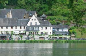 a large white house next to a body of water at Hotel Haus Burg Metternich in Beilstein +35 photos