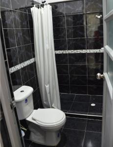 a black tiled bathroom with a toilet and a shower at El Algarrobo in Tocaima