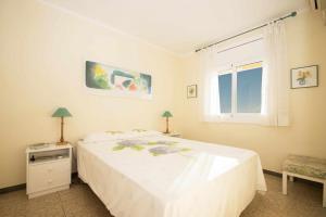 a white bedroom with a bed and a window at Maresme Beach Apartment in Canet de Mar