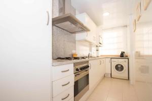 a white kitchen with a stove and a dishwasher at Maresme Beach Apartment in Canet de Mar +18 photos