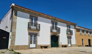 a white building with a green door and balconies at Casa do Terreiro in Barqueiros