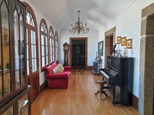 a living room with a red couch and a piano at Casa do Terreiro in Barqueiros
