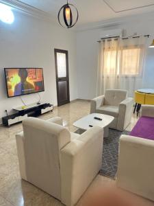 a living room with white furniture and a flat screen tv at Deckon in Avéméné