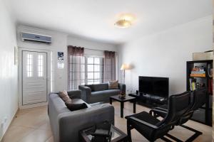 a living room with two couches and a tv at Ideal Villas Residence in Vila Nova De Cacela