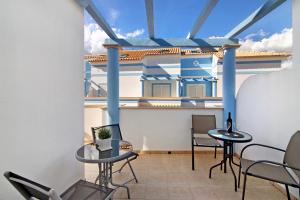 a balcony with two tables and chairs and a house at Ideal Villas Residence in Vila Nova De Cacela